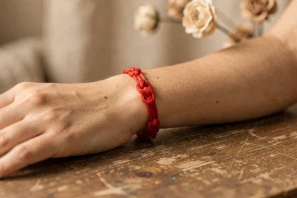 Bracelet fil rouge à 7 nœuds porté au poignet d'une femme, symbole de protection et de chance